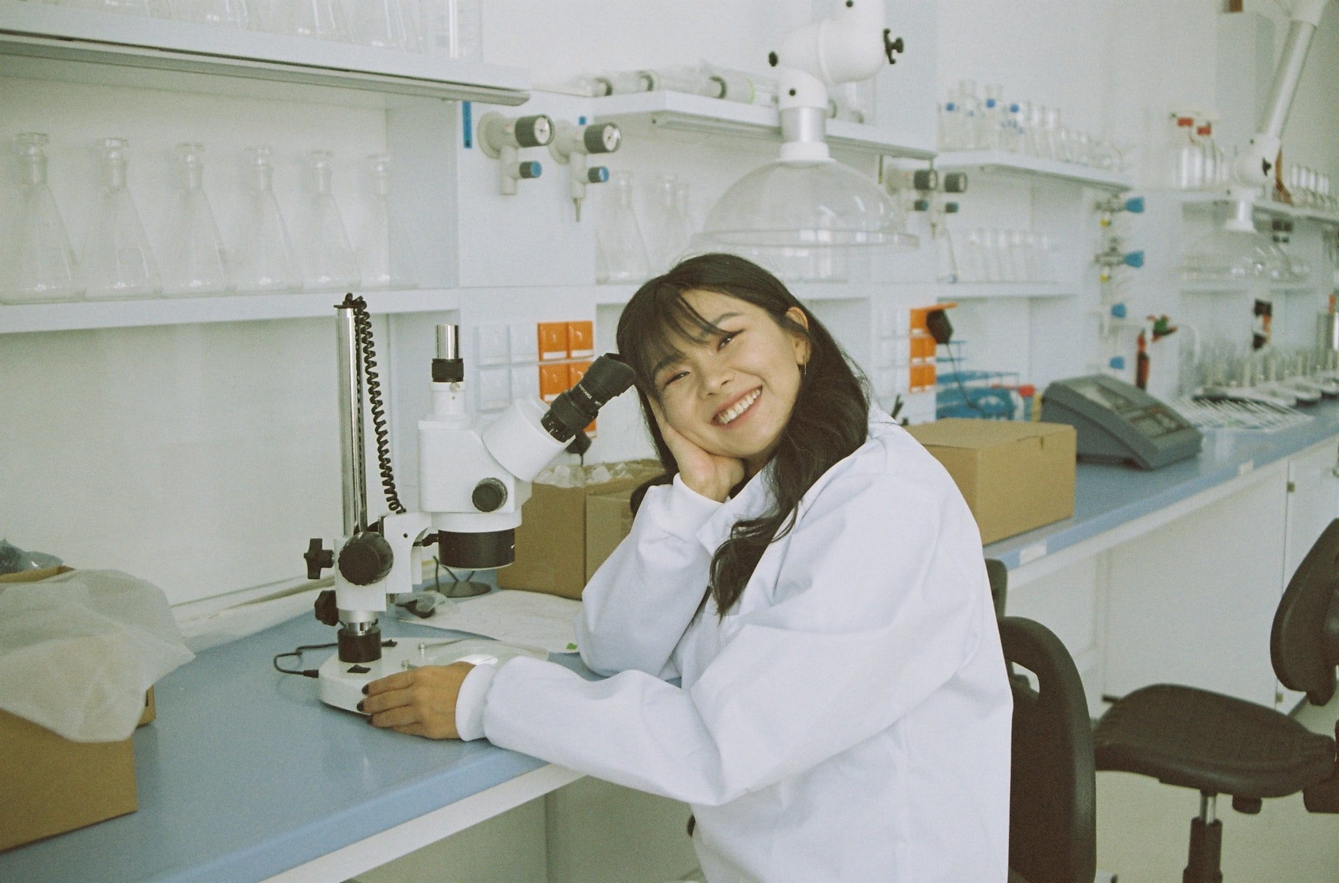เจ้าหน้าที่ห้องปฏิบัติการที่โต๊ะทำงานข้างกล้องจุลทรรศน์